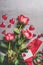 Valentines day, love or dating concept. Red roses bunch with gift box, blank paper greeting card and hearts on gray background , t