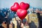 Valentines day in the New York city. man hand holding three reds balloons in form of heart over Manhattan and skyscrapers.