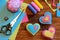 Valentines day ornaments. Felt heart ornaments, scissors, thread, pincushion, thimble, felt sheets and pieces on a wooden table