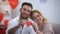 Valentines day preparation, couple smiling and showing to camera red paper heart