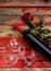 Valentines day. Red wine bottle, glasses and a rose on red wooden background