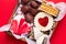 Valentines Day sweets and cookies in wooden box on red background. Chocolate, meringue, marshmallow, linzer cookies, gingerbread.