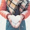 Valentines embrace Womens hands in warm mittens form a snowy heart