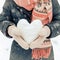 Valentines embrace Womens hands in warm mittens form a snowy heart