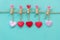 Valentineâ€™s Day. Sewed pillow hearts row border on red, pink and white clothespins at rustic blue pastel wall.