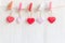 Valentineâ€™s Day. Sewed pillow hearts row border on red, pink and white clothespins at rustic white wood planks