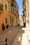 Valletta, Malta, August 2015. A typical street in the old town and a woman opening the door.