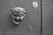 Valletta, Malta, August 2019. Black and white photo of an old doorknob in the form of a satire mask.