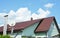 Valley and gable roofing construction with attic windows,  rain gutter, waterproofing. Roof attic house metal tiles roofing with