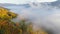 Valley in the mountains covered with morning mist. Aerial view of Ukrainian Carpathians in autumn. Flying over colorful