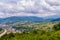 The valley of mountains in which the town stretches along the riverbank, with colored roofs on houses on a cloudy day