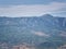 Valley and pine-covered mountain range slope in the afternoon haze and antennas on the top of the peak