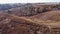 Valley with ravine, single trees and dry grass, aerial view