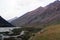 A valley surrounded by mountains with grass slopes and screes in overcast day