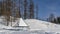 In the valley there is a gazebo with a layer of snow on a pyramidal roof.