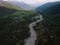 The valley and the town of Mazeri in the distance. Aerial view of the stormy flow of the Dolra River, in the middle of a forest, a