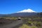 Van driving on road of Conguillio National Park, snow capped peak of Volcano Llaima in the background, Chile