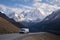 van and its driver, on twisting mountain road, with majestic peaks in the background