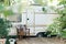 Van mobile home with terrace, House on wheels. Caravan camping. trailer-house on wheels in a green forest garden. trailer