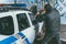 vandal crashing police car with baseball bat while another man