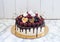 Vanilla cheesecake decorated with melted dark chocolate, fresh berries, cherries, chocolate hearts and meringues