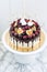 Vanilla cheesecake decorated with melted dark chocolate, fresh berries, cherries, chocolate hearts and meringues