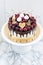 Vanilla cheesecake decorated with melted dark chocolate, fresh berries, cherries, chocolate hearts and meringues