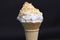 Vanilla ice cream cone with caramel butterscotch nuts topping isolated on black background