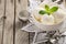 Vanilla ice cream with mint leaves in white bowl on rustic wooden background