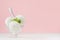 Vanilla ice cream scoops in elegant bowl with green mint, silver spoon in modern stylish pastel pink interior.