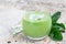 Vanilla, mint, spinach and coconut milk detox green smoothie in a glass, horizontal, copy space