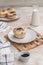 Vanilla muffin with sprinkled cocoa on a white saucer on a light table. Culinary cover, cooking, baking