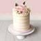 Vanilla pink layered cake with whipped cream flowers on it