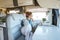 Vanlife people lifestyle. One young adult female relax on the sofa inside a modern cozy motorhome camper van and looking outside