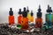 Vape concept. Beautiful colorful vape liquid glass bottles outdoor on stones. Useful as background or electronic cigarette
