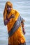 Varanasi, India, 16 november, 2019 / Life on the Ganges: woman in a bright yellow or orange sari bathing in the Ganges as