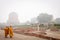 VARANASI, INDIA - DECEMBER 2, 2016: Buddhist monks and tourists come to visit and pray in the misty morning at Dhamekh Stupa.