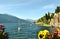 Varenna lakefront and the town, ornamental flowers, sailing boat in a spring sunny day.