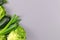 Variation of green vegetables including spring onion, zucchini and romaine lettuce in corner of gray background with blank copy sp