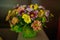 Varied colors blossoms in a rustic bridal arrangement positioned against a dark background