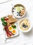 Varied sweet and savory breakfast - bacon with egg and vegetables, spinach, yogurt with granola and fruit, vegetarian