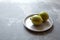 Variegated pink lemons with green-striped rind in grey plate on concrete background with copy space