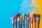 A variety of artist paint brushes laid out on a vibrant background, in art class extracurricular hobby at school or