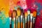 A variety of artist paint brushes laid out on a vibrant background, in art class extracurricular hobby at school or