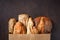 Variety breads with seeds in a brown kraft paper wrapper on a dark wooden surface with copy space. Food bread background. Bakery