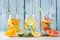 Variety of citrus infused detox water drinks in mason jars against blue wood