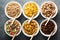 Variety of cold cereals in white bowls with spoons