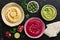 A variety of colored hummus in a plate, pomegranate, olives and pita on a dark background. Top view, flat lay