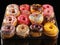 Variety of colorful donuts, freshly baked and adorned with glaze and sprinkles, are showcased in a tempting array