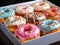 Variety of colorful donuts, freshly baked and adorned with glaze and sprinkles, are showcased in a tempting array